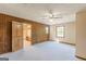 Spacious bedroom with paneled accent wall, carpet flooring, ceiling fan, and a large closet area with custom shelving at 13819 Woolsey Rd, Hampton, GA 30228