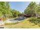 Backyard featuring a covered pool, surrounded by mature trees and beautiful landscaping at 13819 Woolsey Rd, Hampton, GA 30228