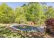 Backyard pool covered for the off-season surrounded by a deck and mature trees and plantings at 13819 Woolsey Rd, Hampton, GA 30228