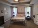 Bedroom featuring a tray ceiling, large bed, side tables, and natural light at 3999 Cumberland Se Trl, Conyers, GA 30094