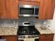 Kitchen with a stainless steel stove, microwave, granite countertops, and wooden cabinets at 3999 Cumberland Se Trl, Conyers, GA 30094