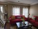 Cozy living room with hardwood floors, a red couch, decorative curtains, and neutral paint at 3999 Cumberland Se Trl, Conyers, GA 30094