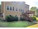 Back exterior featuring multi-pane windows, wooden deck and stairs and lush shrubs at 1275 Mill Shyre Way, Lawrenceville, GA 30043