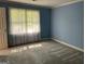 Bedroom with blue walls and grey carpet with sunlight filtering in through the window at 140 Julie Rd, Tyrone, GA 30290