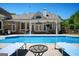 Covered patio with an outdoor kitchen and ceiling fans overlooks an in-ground pool with deck chairs, perfect for entertaining at 207 Jamestown Ave, Jonesboro, GA 30236