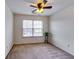 A cozy bedroom featuring neutral walls, plush carpeting, and a window for natural light and a ceiling fan at 7750 Carnegie Dr, Fairburn, GA 30213