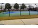 Outdoor tennis court surrounded by a secure fence, trees, and nearby residential buildings at 7750 Carnegie Dr, Fairburn, GA 30213