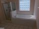 Bathroom with a large soaking tub, shower, and a window letting in plenty of light at 7541 Coddington Ct, Riverdale, GA 30274