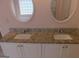 Bathroom vanity features double sinks, granite countertop, white cabinetry, and oval mirrors at 7541 Coddington Ct, Riverdale, GA 30274