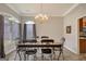 Sun-filled dining space with a modern light fixture, wood table, and open access to other rooms at 203 Collierstown Way, Peachtree City, GA 30269