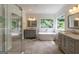Elegant bathroom featuring dual vanities, a freestanding tub, a glass-enclosed shower and a tranquil view at 6205 Collingham Trce, Cumming, GA 30040