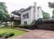 Back exterior showing a multi-level deck and a brick patio, surrounded by greenery and a large yard at 6205 Collingham Trce, Cumming, GA 30040