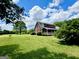 Brick home with a large, lush green lawn and a covered back porch, surrounded by mature trees and blue skies at 238 Marks Rd, Mansfield, GA 30055