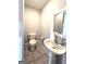 A well-lit half bathroom featuring tile flooring, pedestal sink, and toilet with convenient paper holder at 238 Marks Rd, Mansfield, GA 30055