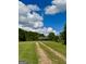 Scenic view of a home down a long gravel drive, surrounded by a sprawling green lawn and mature trees under blue skies at 238 Marks Rd, Mansfield, GA 30055