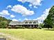 Classic brick home with lush front lawn, accented by mature trees, patriotic flag, and a charming red barn at 238 Marks Rd, Mansfield, GA 30055