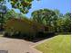 Side exterior view of a single-story home with mature trees, lush lawn, and side patio at 1710 Crumbley Rd, Mcdonough, GA 30252