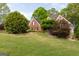 View of a brick home from across a spacious, green lawn with mature trees, highlighting its curb appeal at 1270 Tribble Walk Ct, Lawrenceville, GA 30045