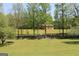 Pastoral view of a well-kept barn in a large open pasture, surrounded by a natural fence and lush trees at 288 Trickum Creek Rd, Tyrone, GA 30290