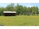 Picturesque pasture with a barn and horses grazing, with a home visible in the distance, under a canopy of green trees at 288 Trickum Creek Rd, Tyrone, GA 30290