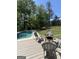 Inviting backyard pool with a cozy deck area featuring comfortable seating and a modern fire pit, surrounded by lush greenery at 288 Trickum Creek Rd, Tyrone, GA 30290
