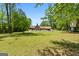 Spacious and manicured backyard with a view of the home, pool, treehouse, and green grass at 3222 Bay View Dr, Jonesboro, GA 30236