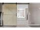 Bright bathroom with a barn door entrance showcasing a large soaking tub and ceramic tile flooring at 3222 Bay View Dr, Jonesboro, GA 30236