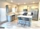 Bright kitchen with white cabinets, stainless steel appliances, an island and wood grain vinyl flooring at 169 Cabin Way, Hampton, GA 30228