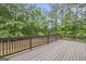 Spacious wooden deck with brown railing showcases views of a lush, fenced backyard and surrounding mature trees at 1085 Crown River Pkwy, Mcdonough, GA 30252