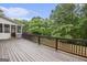 Wide wooden deck with brown railing overlooks a fenced yard and wooded area, perfect for outdoor living and entertainment at 1085 Crown River Pkwy, Mcdonough, GA 30252