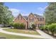 Traditional brick home featuring a manicured lawn, mature trees, and a charming red front door at 1085 Crown River Pkwy, Mcdonough, GA 30252