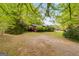View of the front yard and exterior of the red home surrounded by mature trees and landscaping at 362 Highway 113, Temple, GA 30179