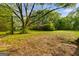 View of the front yard and exterior of the red home surrounded by mature trees and landscaping at 362 Highway 113, Temple, GA 30179