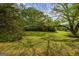 View of the front yard and exterior of the red home surrounded by mature trees and landscaping at 362 Highway 113, Temple, GA 30179