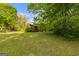 View of the front yard and exterior of the red home surrounded by mature trees and landscaping at 362 Highway 113, Temple, GA 30179