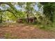 View of the front yard and exterior of the red home surrounded by mature trees and landscaping at 362 Highway 113, Temple, GA 30179
