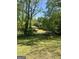 Wide shot of backyard featuring mature trees, partially obscuring a neighboring home, creating a serene setting at 3143 S West St, Covington, GA 30014