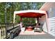 Inviting outdoor deck area, furnished with a bench, chairs, and a red canopy for relaxing and enjoying the surrounding greenery at 301 Spruill Bridge Rd, Temple, GA 30179