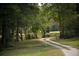 Scenic driveway leading to a tranquil pond surrounded by lush greenery and mature trees at 301 Spruill Bridge Rd, Temple, GA 30179