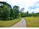 Gravel driveway meandering through a grassy area lined with trees, leading to a secluded property at 301 Spruill Bridge Rd, Temple, GA 30179