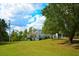 Scenic view of a white house surrounded by lush greenery, tall trees, and a vibrant blue sky with fluffy clouds at 301 Spruill Bridge Rd, Temple, GA 30179