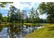 Picturesque pond surrounded by lush greenery and tall trees, reflecting the sky and creating a serene setting at 301 Spruill Bridge Rd, Temple, GA 30179