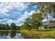 A home is surrounded by lush greenery and overlooks a tranquil pond under a beautiful, cloudy sky at 301 Spruill Bridge Rd, Temple, GA 30179