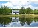 Scenic home exterior reflected in a serene pond surrounded by lush greenery and a bright, cloudy sky at 301 Spruill Bridge Rd, Temple, GA 30179