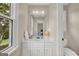 Well-lit bathroom with a single white sink vanity, framed mirror, and window views at 513 Viridian Vw, Peachtree City, GA 30269