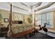 Elegant primary bedroom with a four-poster bed, tray ceiling, large windows, and exercise bike at 608 Wingspread, Peachtree City, GA 30269