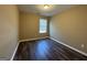 A cozy bedroom with one window and dark vinyl flooring at 1853 Broad River Rd, Atlanta, GA 30349