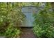 Exterior view of a metal shed surrounded by trees and lush greenery at 1326 Harmony Grove Church Rd, Auburn, GA 30011