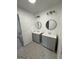 A modern bathroom with double vanities, round mirrors, modern lighting, and stylish tile flooring at 2873 Shoals Hill Ct, Dacula, GA 30019
