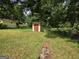 View of a green backyard with a shed enclosed by a chain link fence and surrounded by trees at 502 S Evelyn Nw Pl, Atlanta, GA 30318